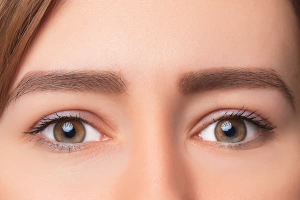 A close up shot of a woman with hazel eyes and combination eyebrows.