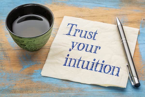 A cup of coffee next to a napkin that says "trust your intuition"