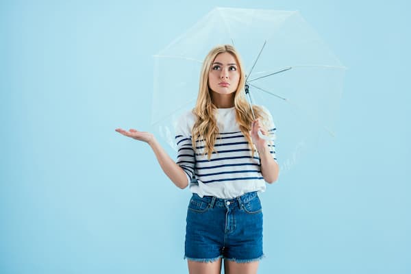 A girl standing under an umbrella.