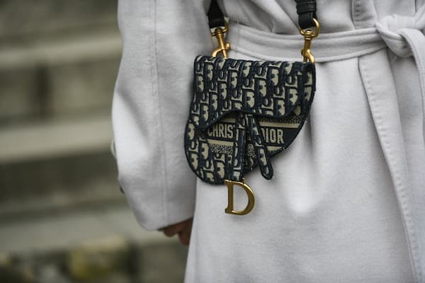 A woman carrying a black and tan Dior handbag.
