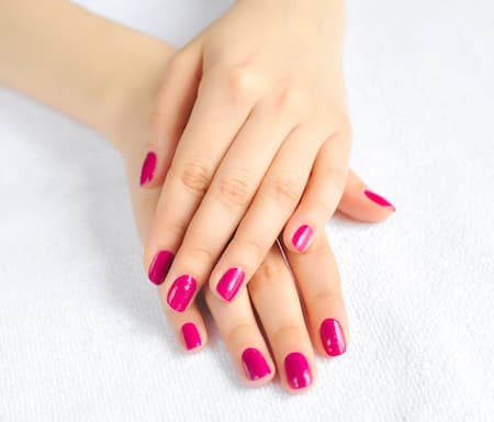 A woman's hands with pink nail polish.