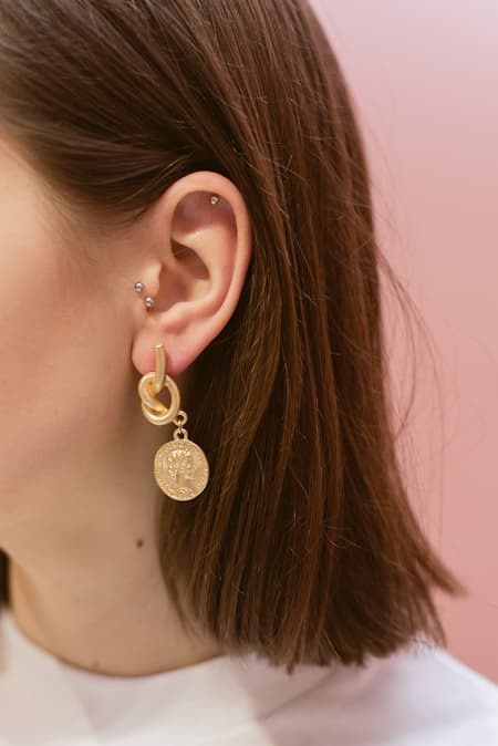 A woman wearing gold plated hypoallergenic earrings.