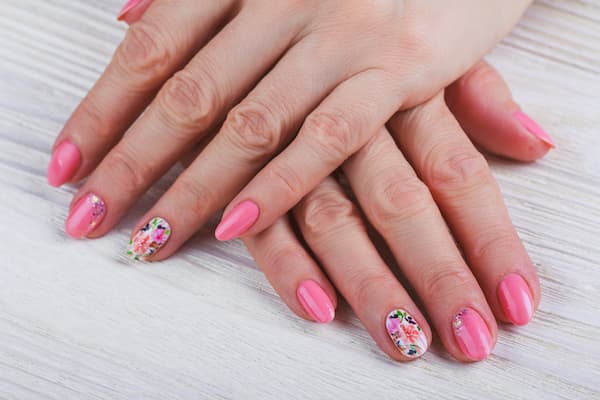 A womans hands after a pink dip manicure.