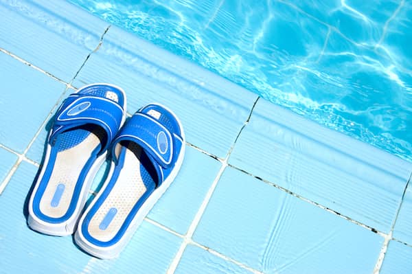 A pair of womens slides sitting next to a pool.