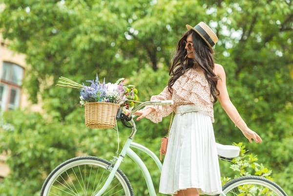 A woman in a boho outfit standing next to a bicycle.