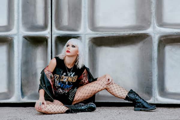 A woman sitting on the ground wearing a punk rock grunge outfit.