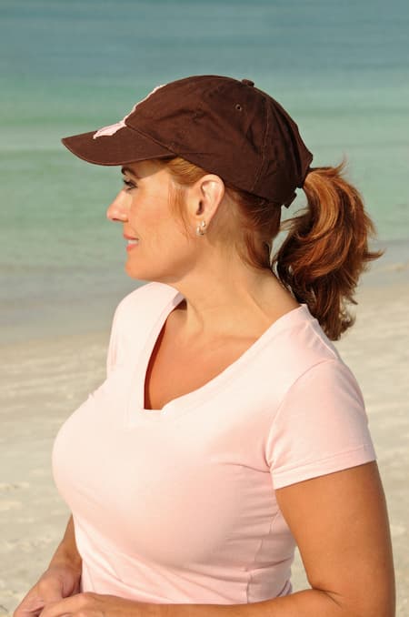 A woman on the beach wearing a hat and tshirt