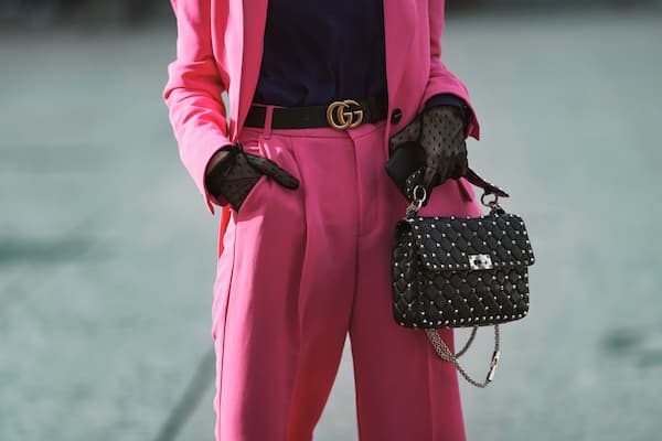 A woman wearing a pink suit and a black Gucci belt.