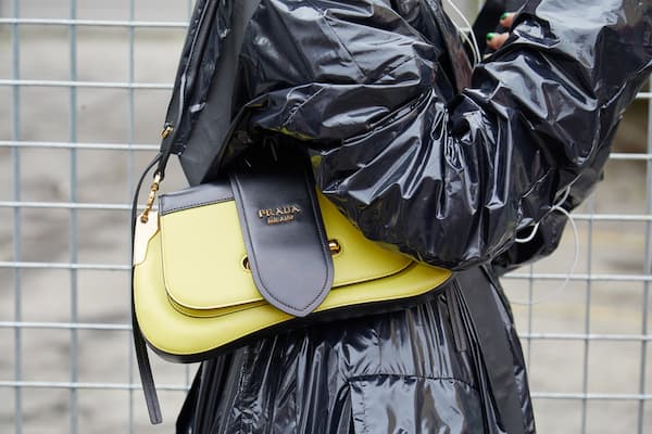 A woman carrying a yellow and black Prada handbag.