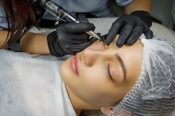 A woman getting a permanent eyeliner tattoo.