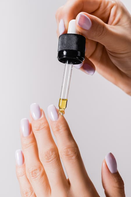 A woman applying cuticle oil to her nail.