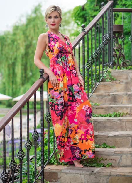 a woman wearing a floral maxi dress standing on the stairs.