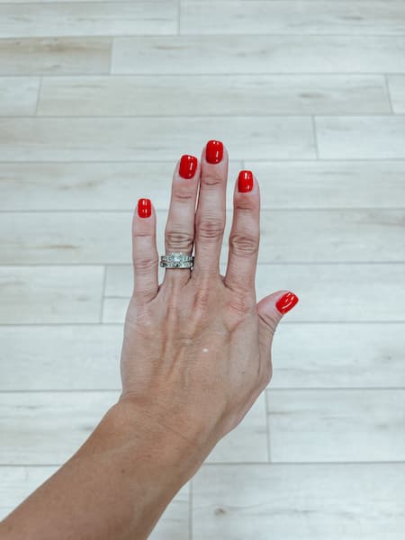 The hand of a woman with red nail polish.