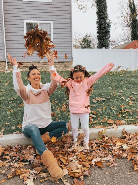 A mother and daughter throwing leaves.