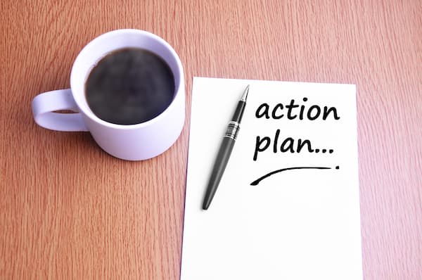 A paper that says "action plan" next to a cup of coffee.
