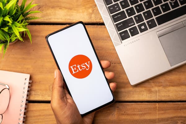 A person a phone with the etsy logo on the screen.
