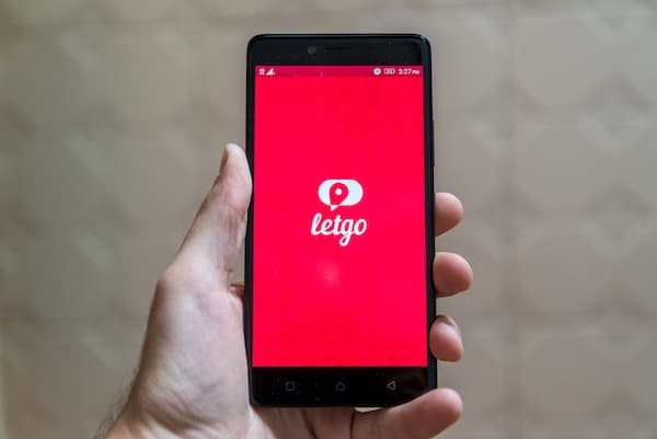 A person holding a phone with the letgo app loading on the screen.