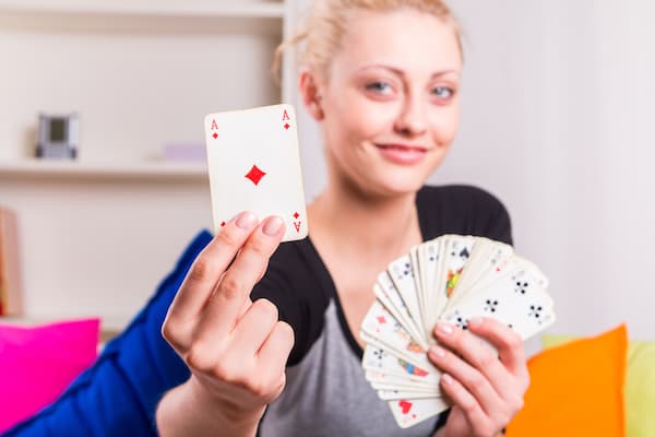 A woman holding up an ace from a deck of cards.