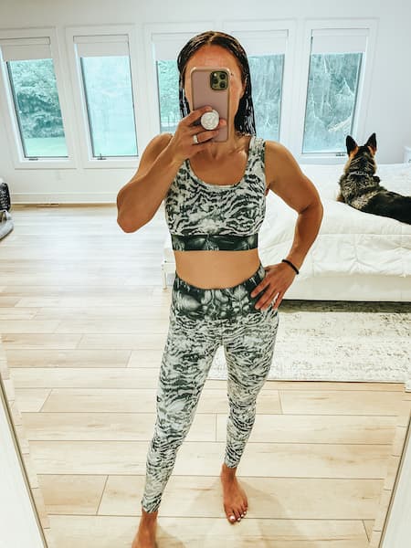 A woman taking a selfie wearing a green sports bra and leggings set from Fabletics. 