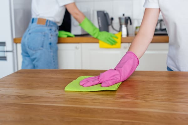 Two women cleaning with rubber gloves on.