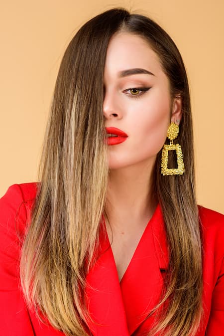 A beautiful woman wearing red lipstick and big drop earrings.