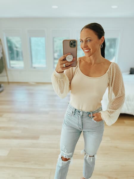 A woman wearing mom jeans and a mesh sleeve blouse